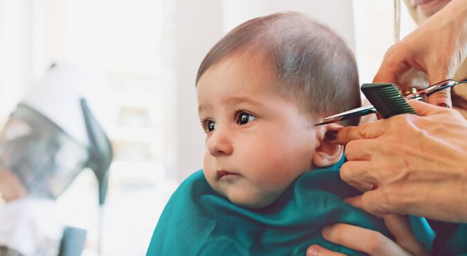 Bebê sentado recebendo corte de cabelo profissional