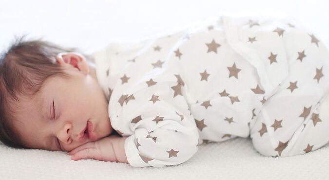 Bebê dormindo de bruços em colchão branco