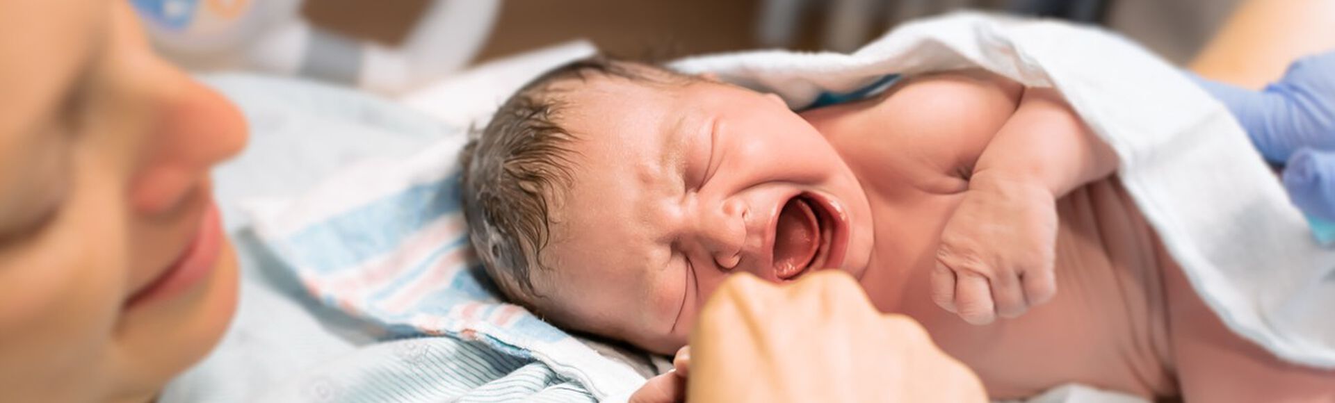 Mulher branca logo após parto com bebê recém-nascido nos braços
