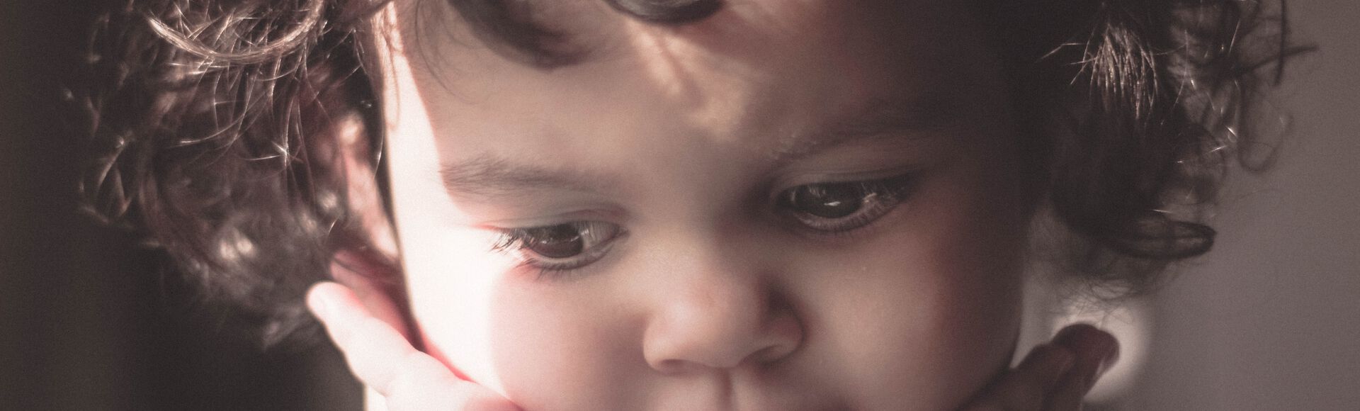 Criança com as maõs no rosto demonstra excesso de timidez na infância