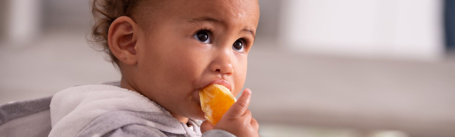 Criança sentada comendo fruta