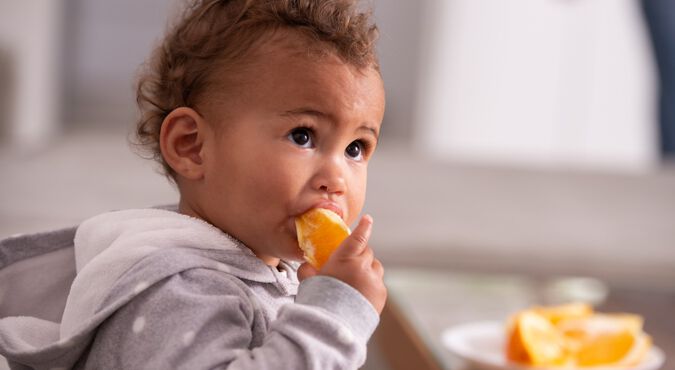 Criança sentada comendo fruta