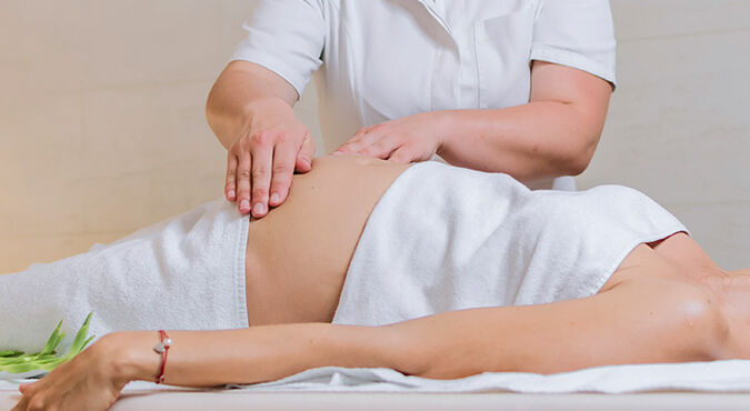 Mulher grávida deitada recebendo massagem na barriga