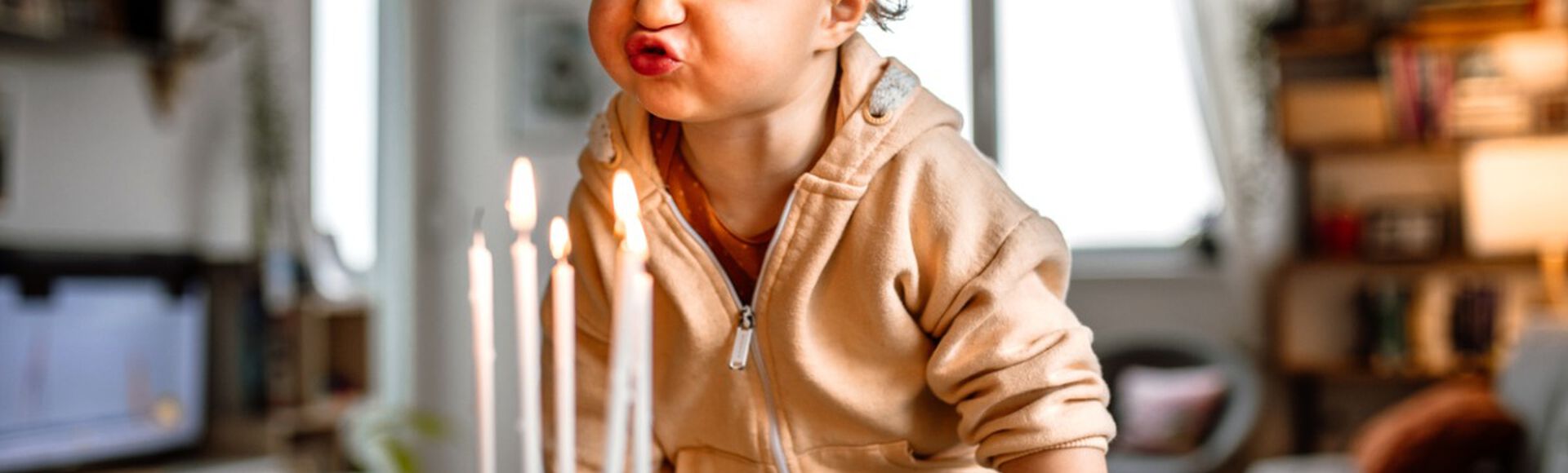 Criança pequena soprando velas em bolo de aniversário
