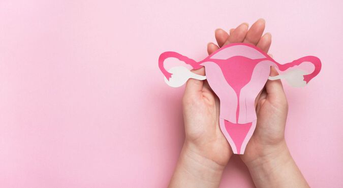 Mulher segurando desenho de útero sobre fundo rosa