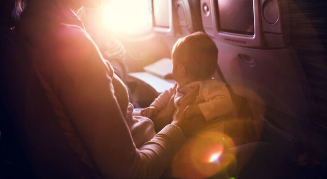 Mãe sentada em poltrona de avião com bebê no colo
