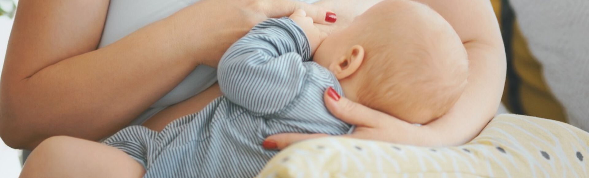 Mãe amamentando bebê posicionado sobre almofada de amamentação