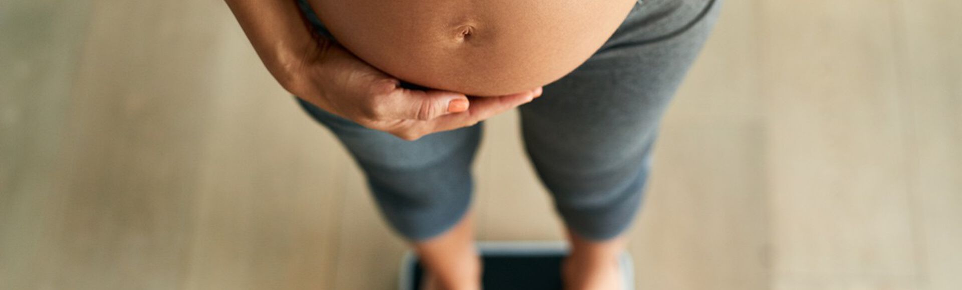 Mulher grávida com barriga em evidência sobre balança