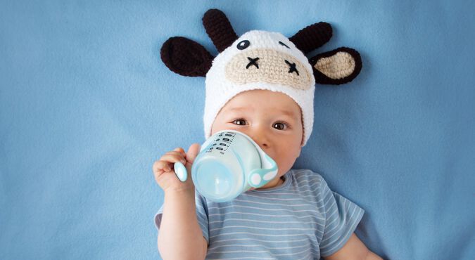 bebê usando touca de vaquinha, deitado e tomando leite