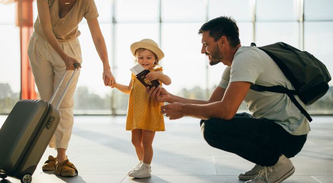 Criança em pé rodeada por pais segurando documentos para viajar em aeroporto