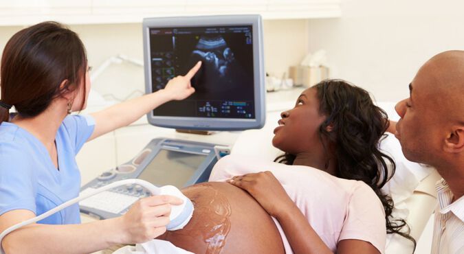 Mulher negra realizando ultrassom em companhia do parceiro