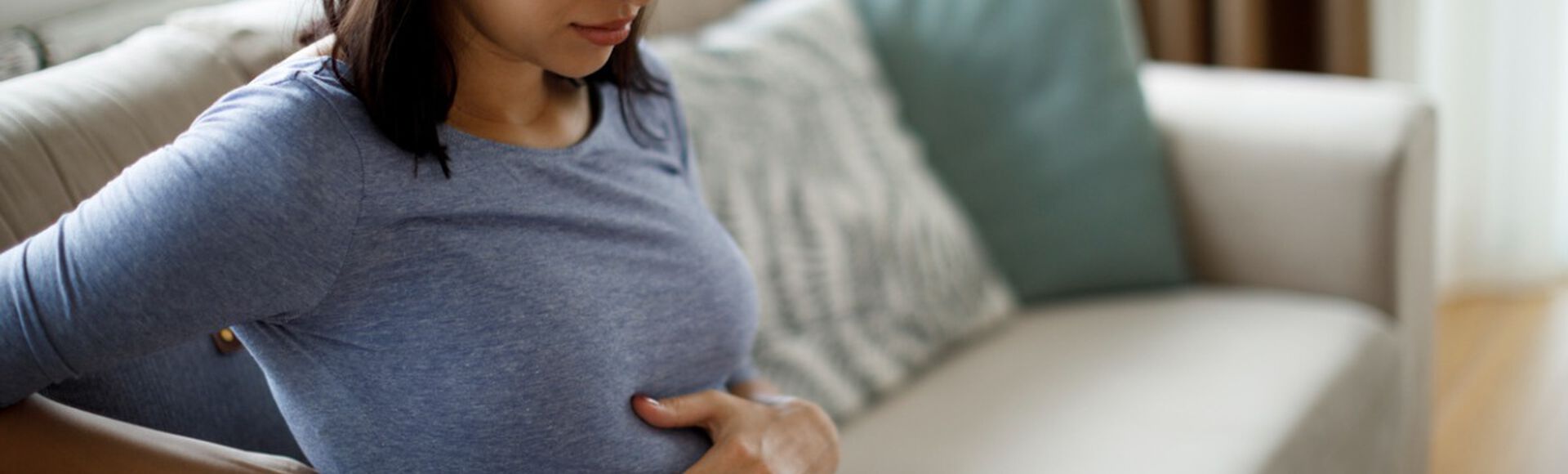 Mulher grávida com maos na barriga em sinal de desconforto