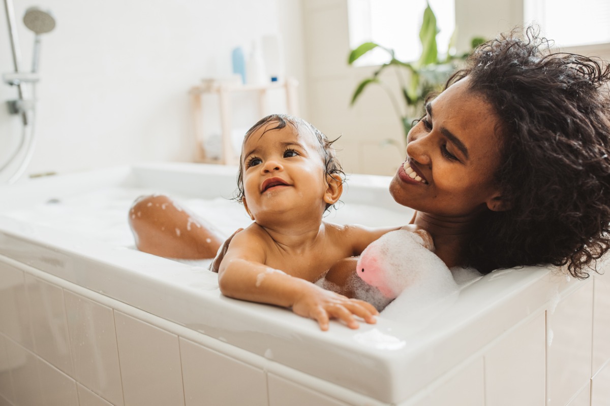 Mãe e bebê na banheira com espuma durante banho